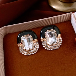 Detail of vintage enamel earrings with rhinestones on a red velvet cushion in a gift box