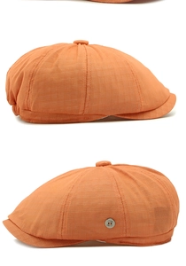 Detail view of the breathable orange mesh fabric and metal side button on the newsboy hat