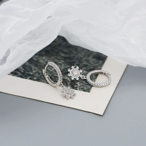 Macro shot of 925 silver starburst earrings with zircon inlay and snowflake pendant