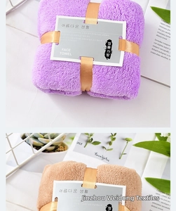 Detailed close-up of thick coral fleece face towels with gold ribbon and gift packaging