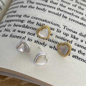 Close-up of gold and silver heart studs with mother of pearl and beaded edges on an open book