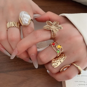 Detailed view of bohemian gold rings with pearls and colorful gemstones on model's hand