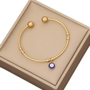 Golden open evil eye bead bangle with blue enamel charm on beige leather jewelry box
