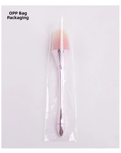 Detail view of pink gradient makeup brush with protective mesh net in OPP bag packaging