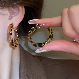 Macro shot of large round leopard print resin earrings with wavy edges and tortoiseshell texture
