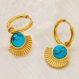 Macro detail of gold hoop earring with turquoise stone inlay and sunburst texture