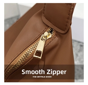 Detail of golden zipper and fine stitching on brown lychee grain faux leather tote bag