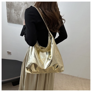 Chic metallic gold tote bag in soft PU leather shown on shoulder in a minimalist studio