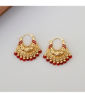 Detailed macro view of retro hollow metal floral earrings with red beads and golden finish