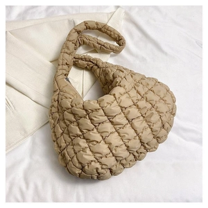 Macro shot of beige quilted dumpling bag with soft padded texture and woven handle