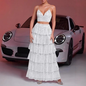 Detailed view of white sequined two-piece dress with tiered skirt set by a luxury car