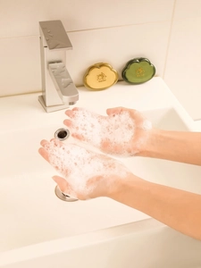 Action shot showing rich soap foam lathering from cloud-shaped soap flakes in a bathroom