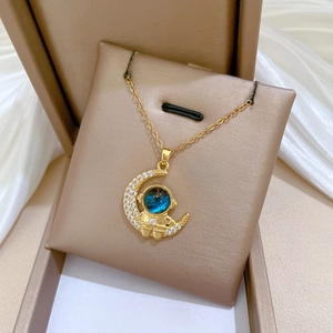 Close-up of gold astronaut on crescent moon pendant with crystals in a jewelry box