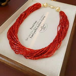 Dettaglio della collana di perline multistrato rosse con accenti dorati in scatola di legno