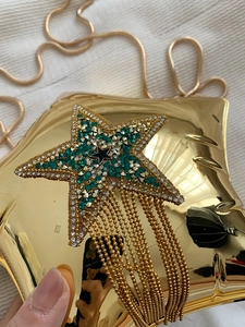 Detail of gold star evening clutch bag featuring rhinestone accents and metal fringe