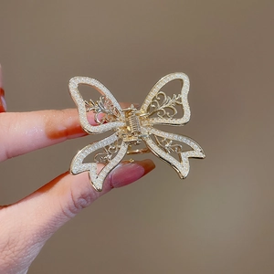 Detailed macro of gold butterfly hair claw with pearls and hollow metal patterns