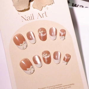 Cat eye press-on nails with white French tips and 3D bow charms on display card