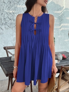 Detail of blue sleeveless dress featuring pleated texture and bow-tie accents