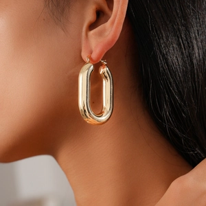 Close-up of a minimalist gold oval hoop earring worn by a model for a stylish look