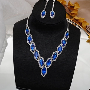 Detailed close-up of bridal dark blue crystal necklace and earrings on a black neck bust