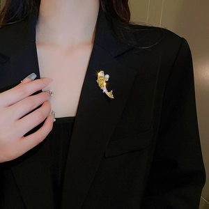 Detail of a gold koi fish brooch with pearls and zircons on a black blazer lapel