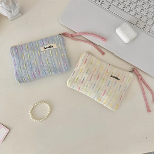 Detail of portable striped knit cosmetic bags with woven texture and zipper closure