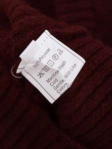 Macro shot of the care label and fabric texture of this burgundy V-neck knit sweater