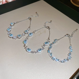 Detailed close-up of three aquamarine zircon bracelets with bow and heart designs
