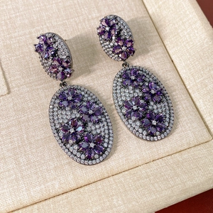 Detailed macro view of vintage oval drop earrings with purple floral crystals and zircons