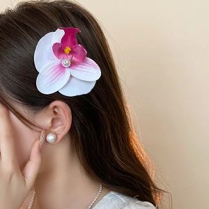 Detail of white orchid hair claw with pearl core on brunette hair side view