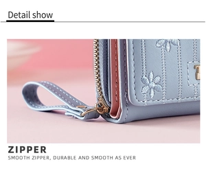 Detailed macro view of smooth metal zipper and floral embroidery on light blue PU leather