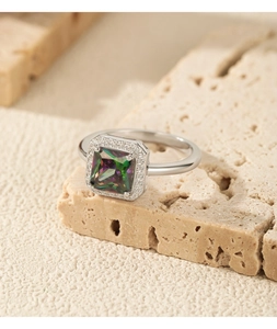 Macro view of a square rainbow zircon ring with silver halo setting on a stone base