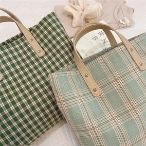 Top view of two plaid canvas tote bags with premium brown leather handles and rivets