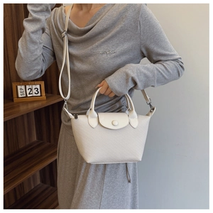 Detail of cream woven leather handbag featuring refined texture and adjustable strap