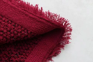 Macro du tissu en tweed bordeaux avec des franges fines et des fils métalliques brillants