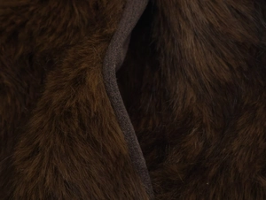 Détail macro de la texture fausse fourrure marron foncé et des coutures de la veste