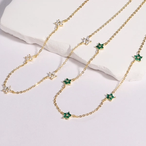 Detailed shot of golden chain necklace with white and green zirconia flower pendants