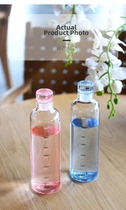 Close-up of glass water bottle with time markers and simple caps on wooden table