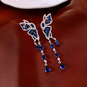 Détail des boucles d'oreilles grue vintage avec pierres bleues et pampilles