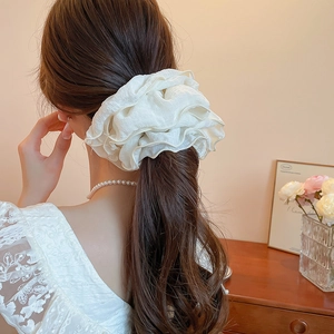 Detail of cream oversized scrunchie with layered ruffle pleats on ponytail