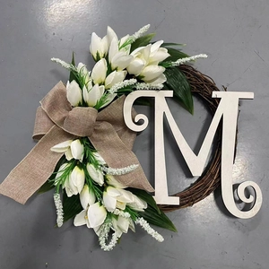 Front view of floral wreath with white tulips, beige linen bow and white wooden letter M