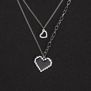 Detail view of double-layered necklace featuring pixelated black heart and hollow heart pendants