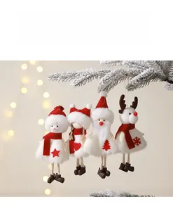 Close-up of four plush Christmas dolls hanging on snowy pine branches with warm lights