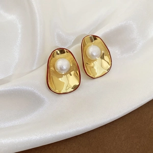 Detail of vintage gold shell earrings with white pearl inlay and red painted edges