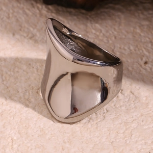 Close-up of sculptural asymmetric thick silver metal ring on textured beige background