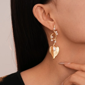 Detail of gold floral leaf earring with imitation pearls worn by a model in profile