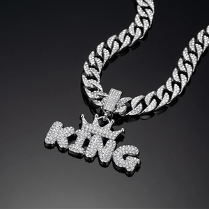Macro shot of a silver iced-out cuban chain necklace with a KING crown pendant charm