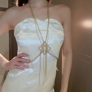 Close-up of golden body chain featuring a pearl and rhinestone flower pendant with tassels