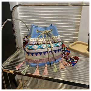Close-up of blue canvas bucket bag featuring ethnic geometric embroidery and tassel details