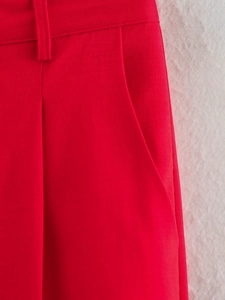 Détail du pantalon de costume rouge avec passants de ceinture, poches italiennes et texture sergée